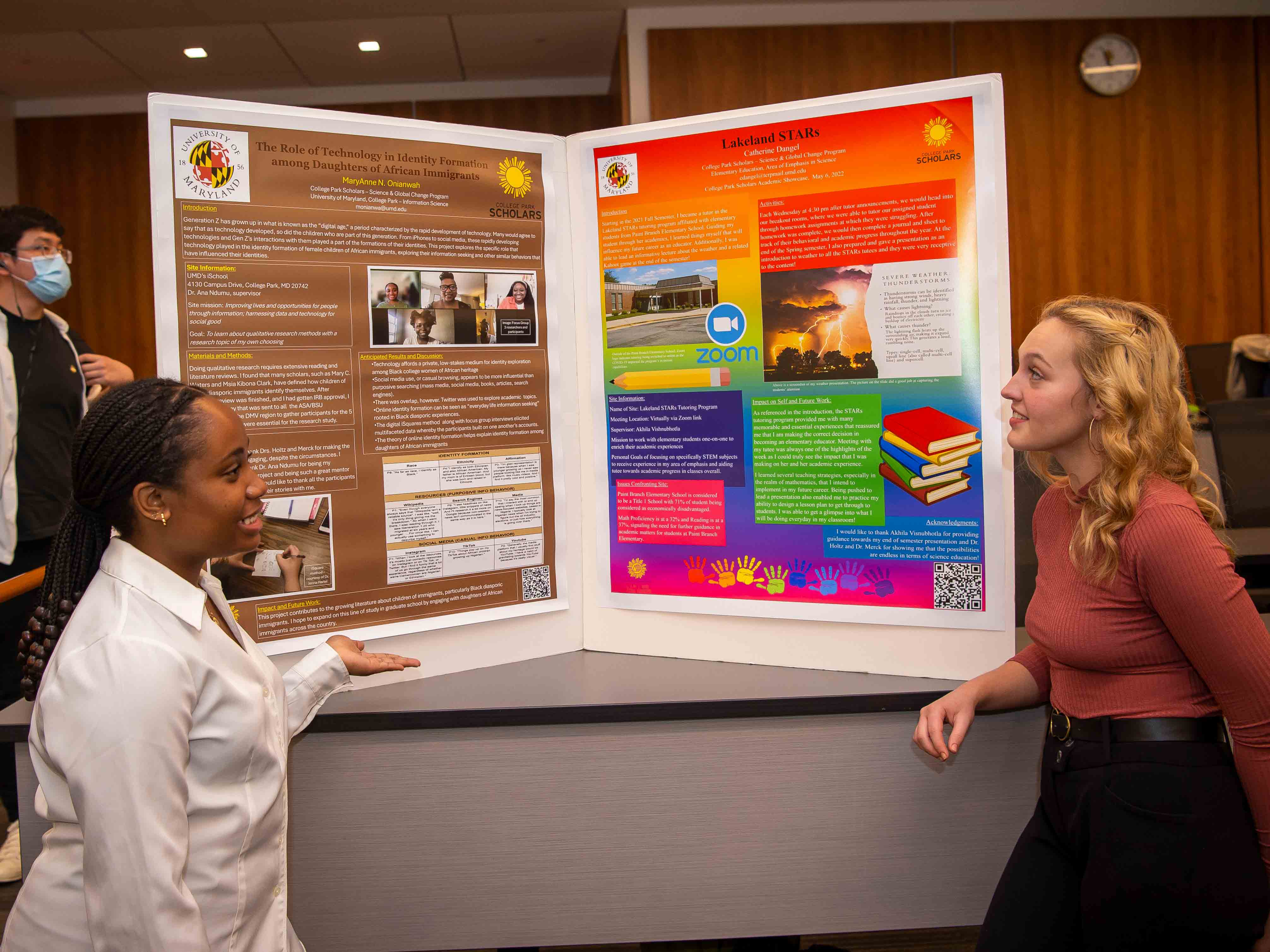 Student in white shirt presents her practicum poster to another student at Academic Showcase