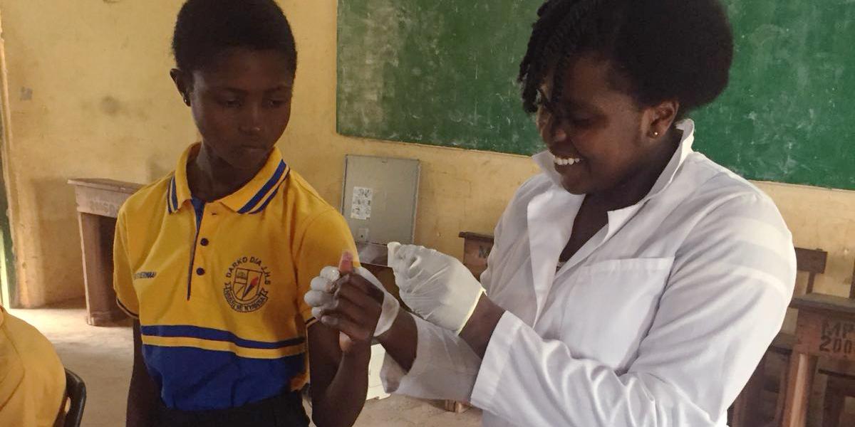 Young woman in lab coat gives girl a band-aid