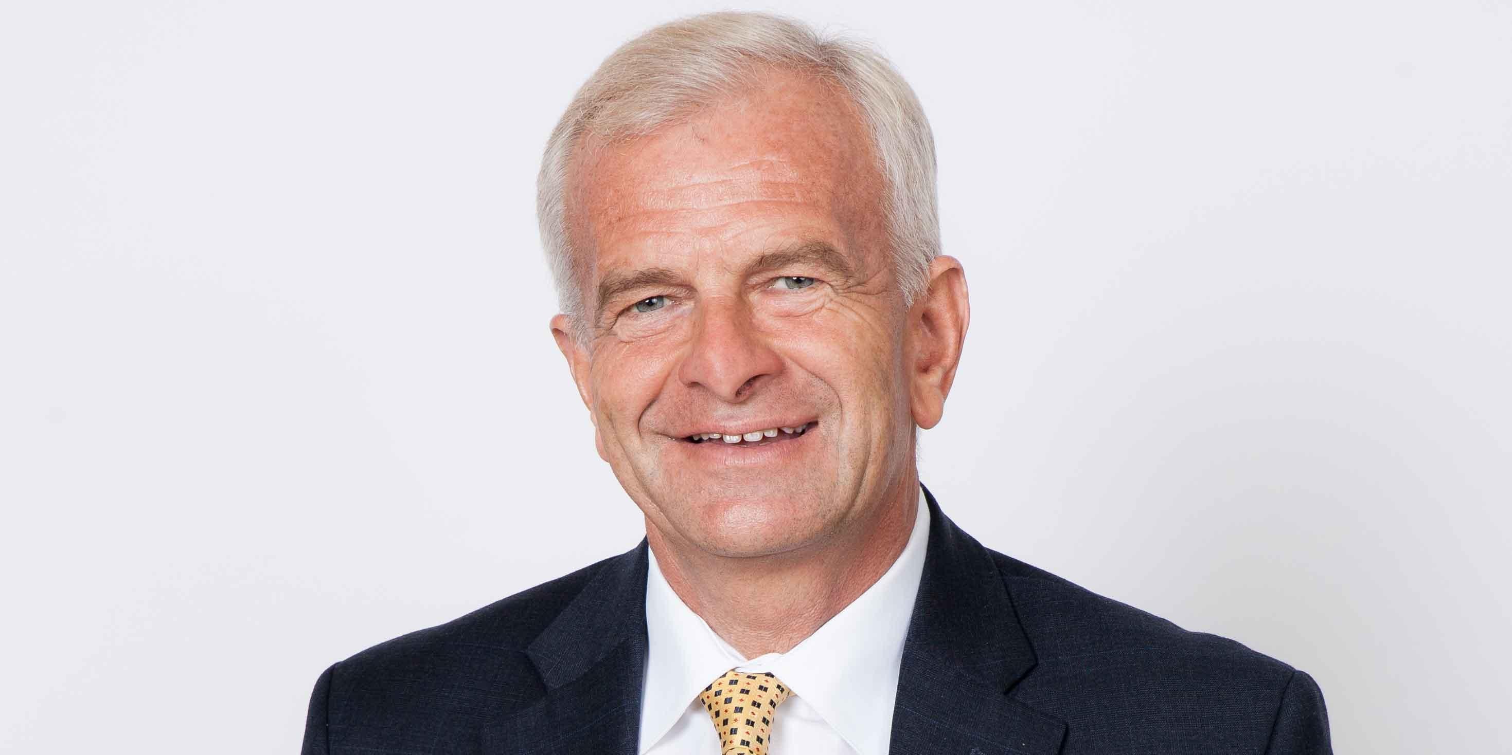 Photo of silver-haired man wearing a dark suit