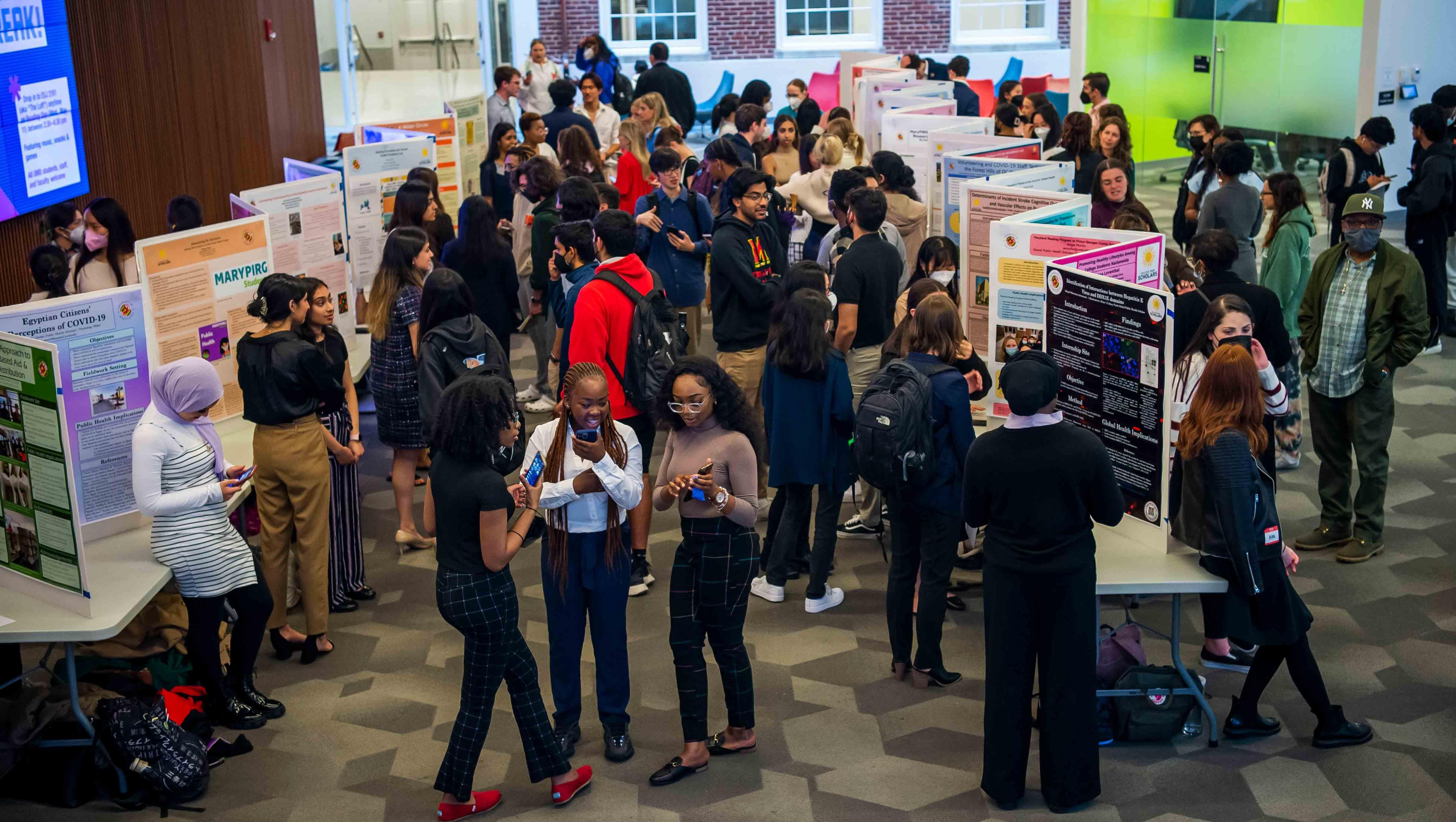 Photo shows room lined with posters and students standing against them