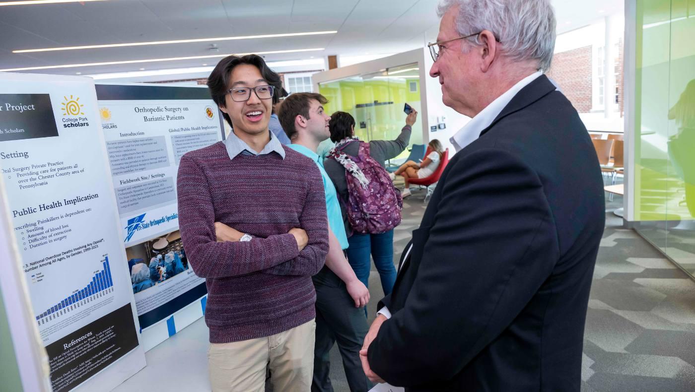 student discusses poster with faculty