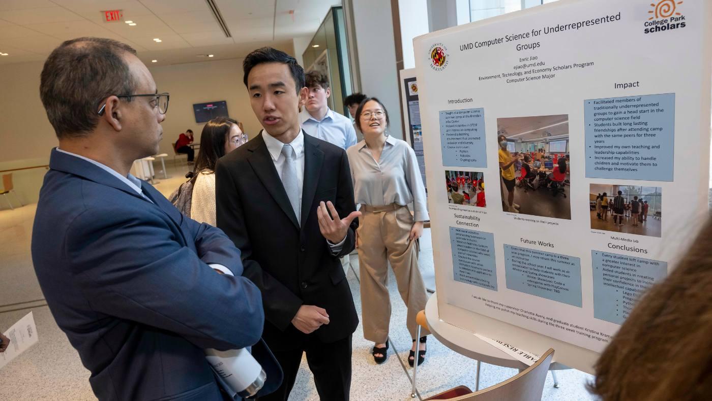 student stands in front of academic showcase posters