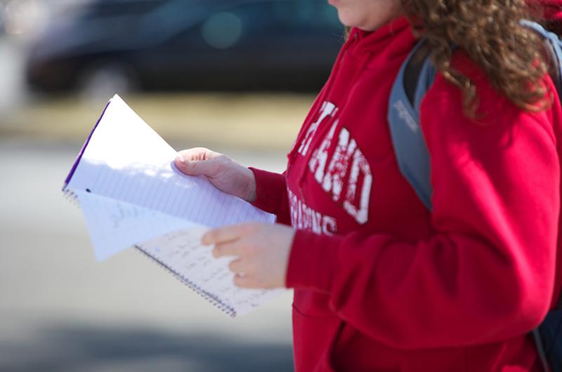 student in red sweatshirt with open notebook