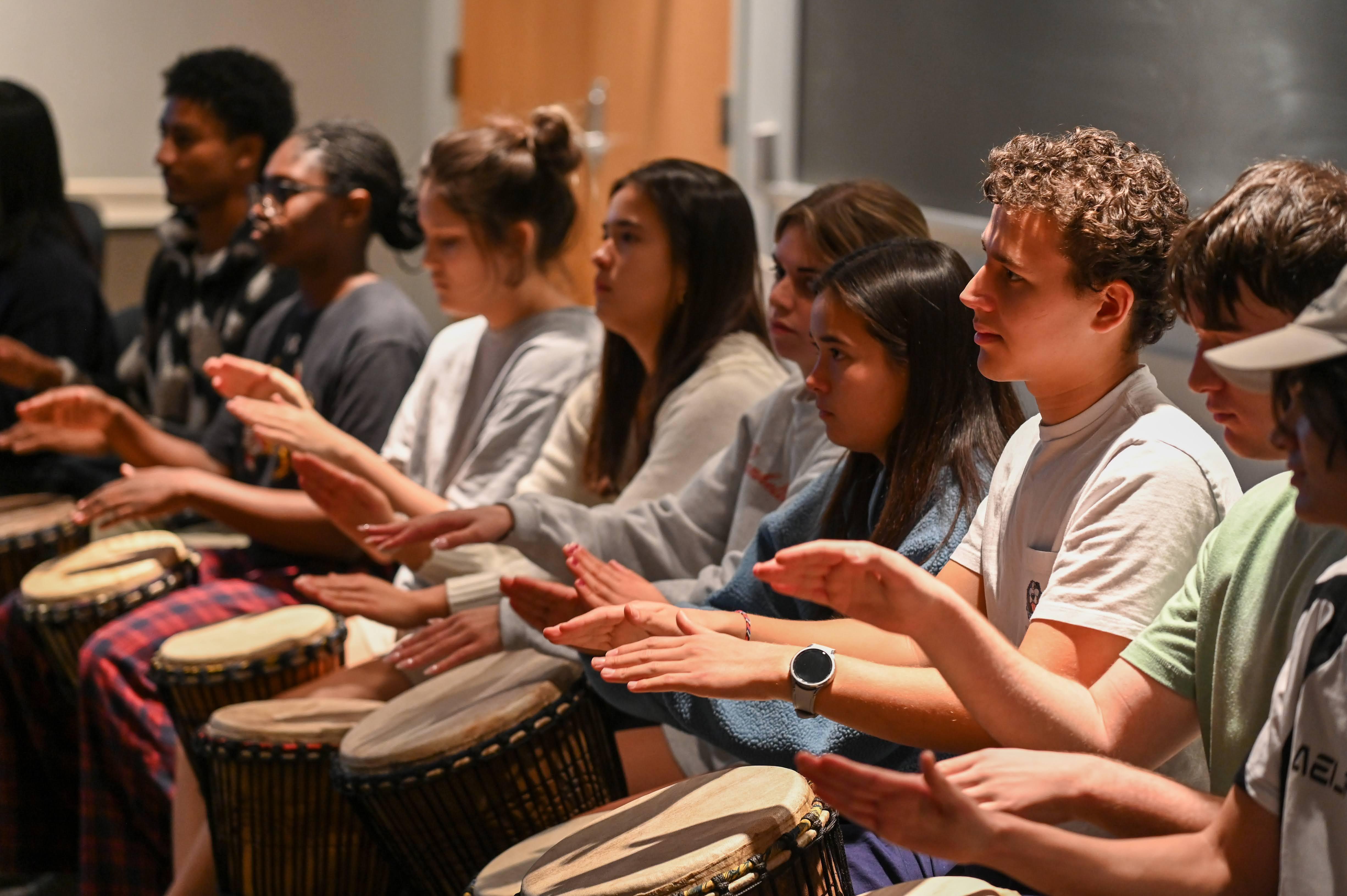 students seated playing drums with hands