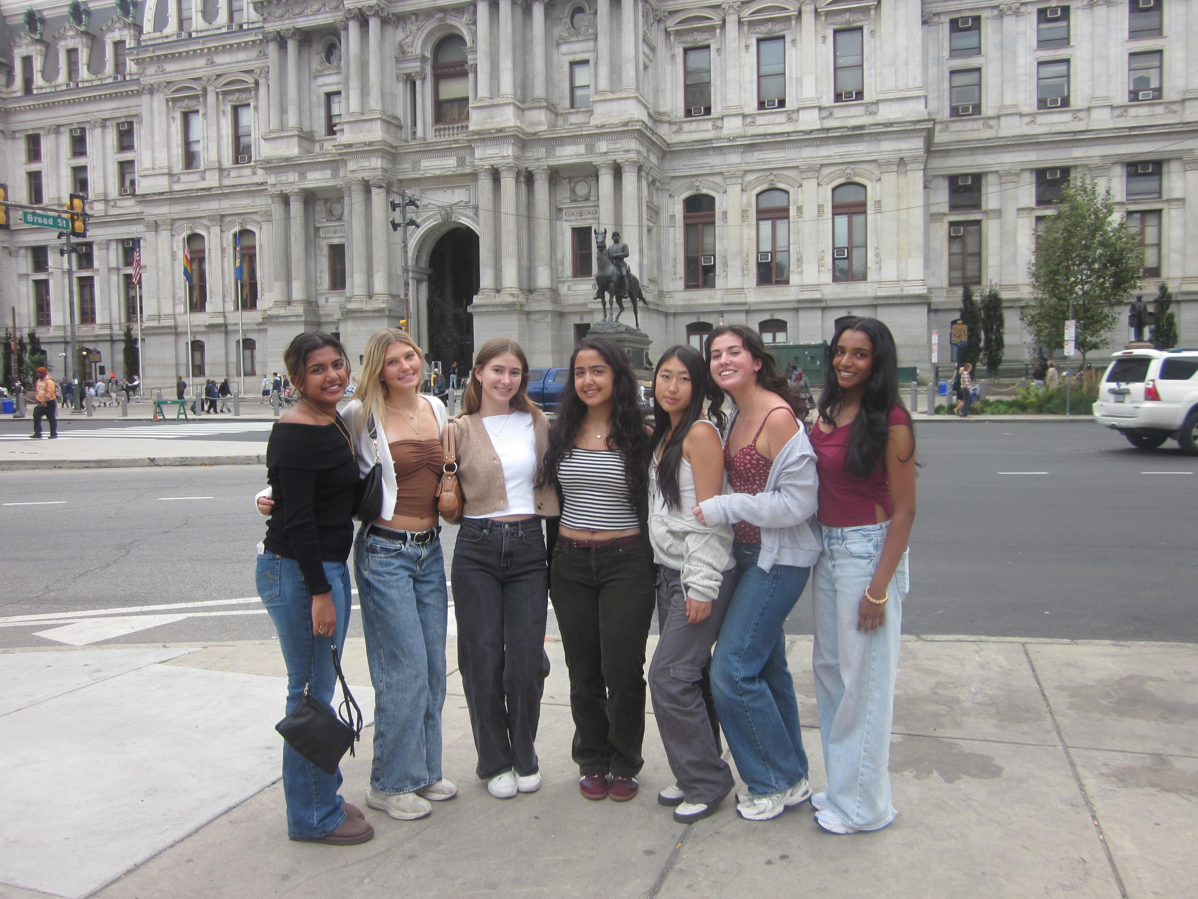 group of women smiling standing near a white columned building