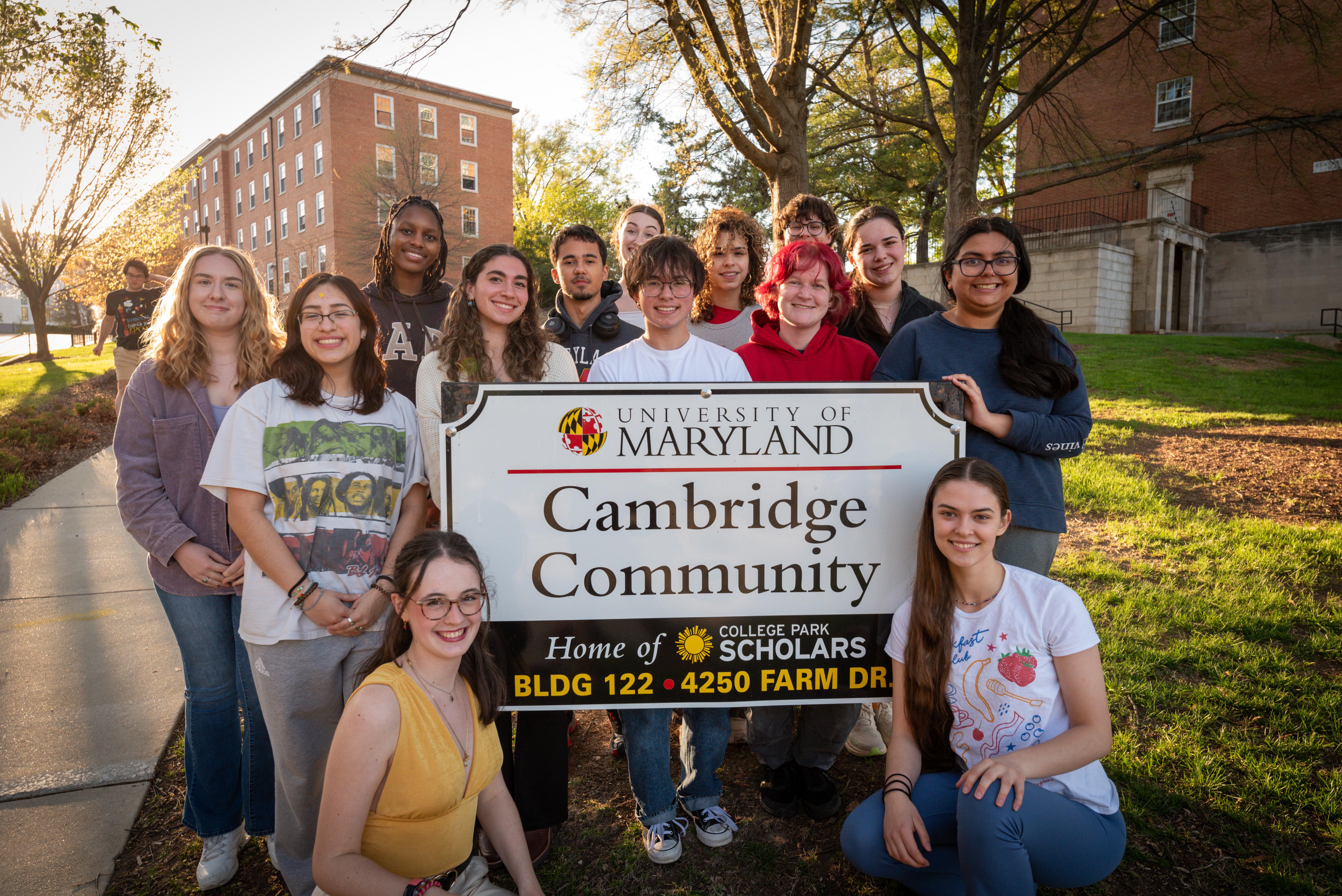 group of students smiling around white Cambridge Community sign