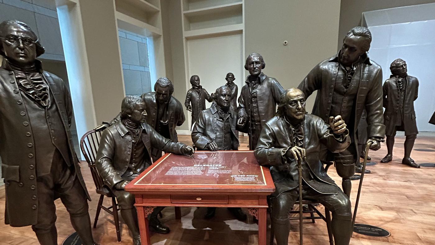 bronze statues of men around a table