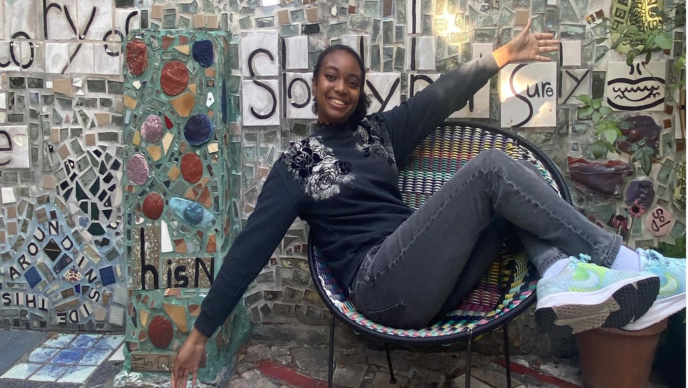 smiling woman laying across a chair with arms extended and legs crossed