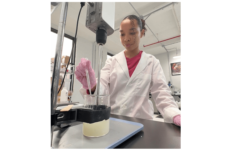 woman in white lab coat with pink gloves holding a syringe