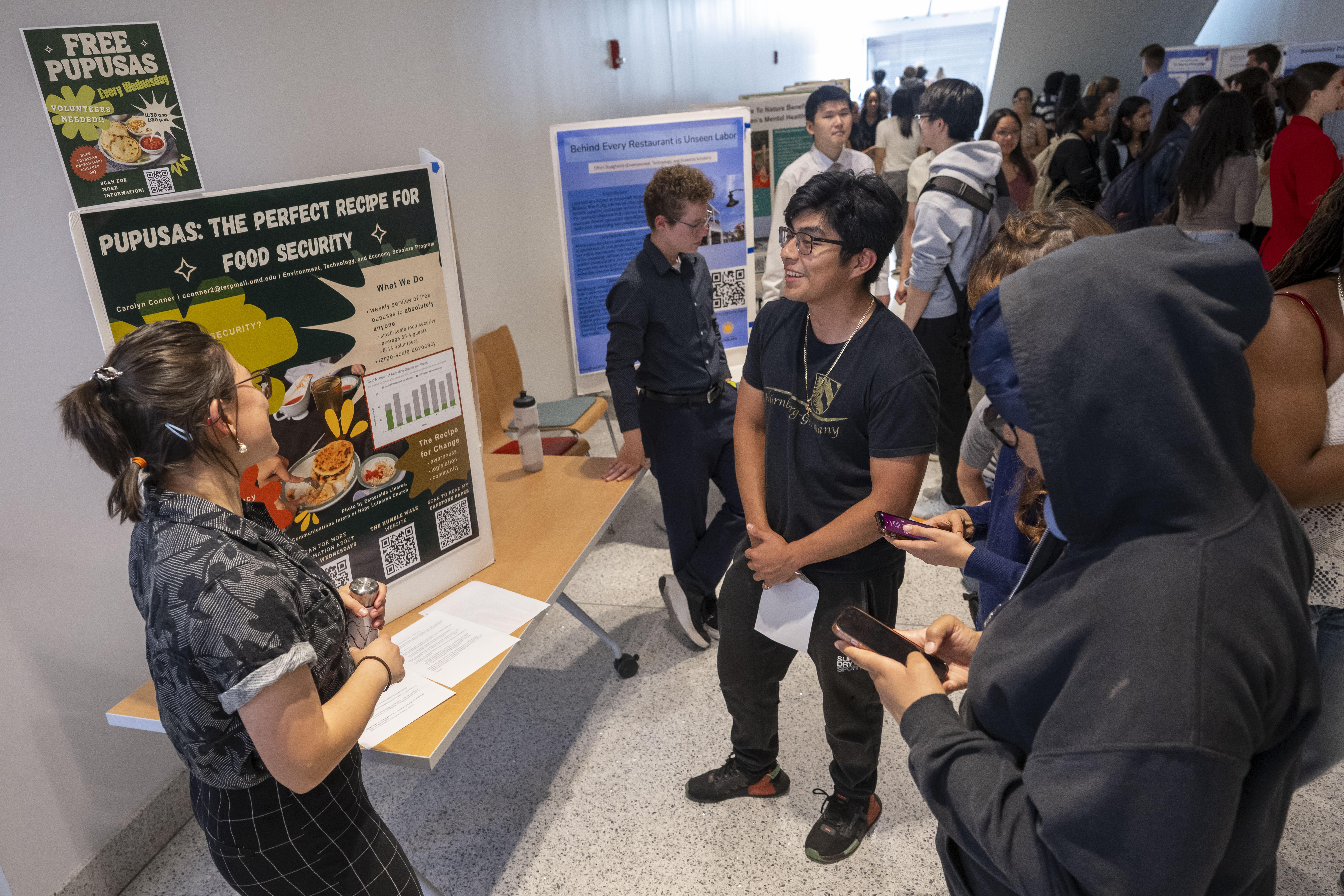 woman in front of posterboard talking to students