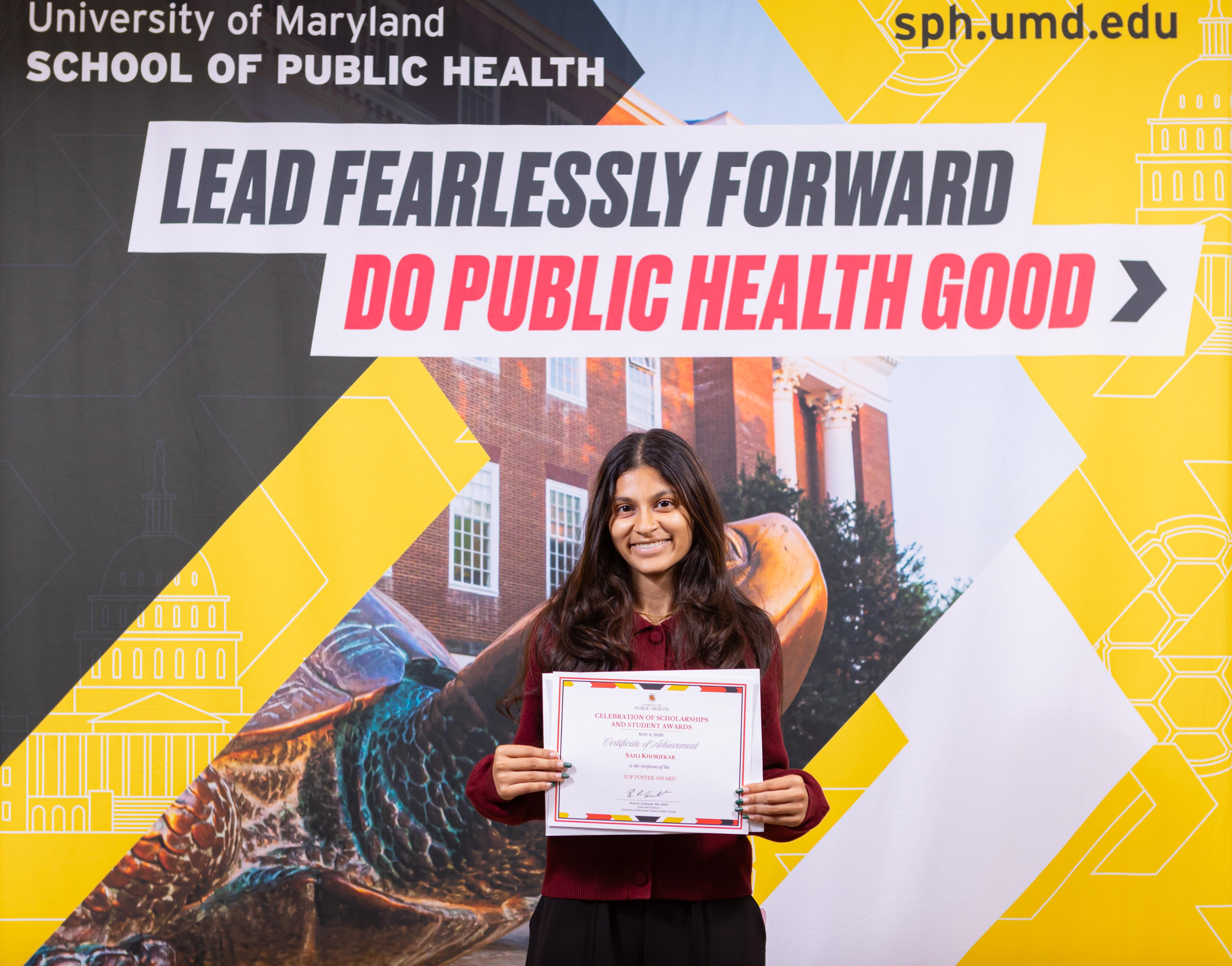 woman holding certificate in front of sign