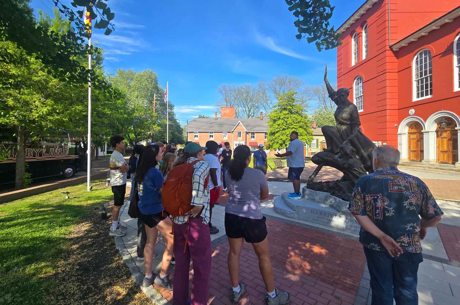 students stand around a Harriet Tubman statue in front of a brick courthouse