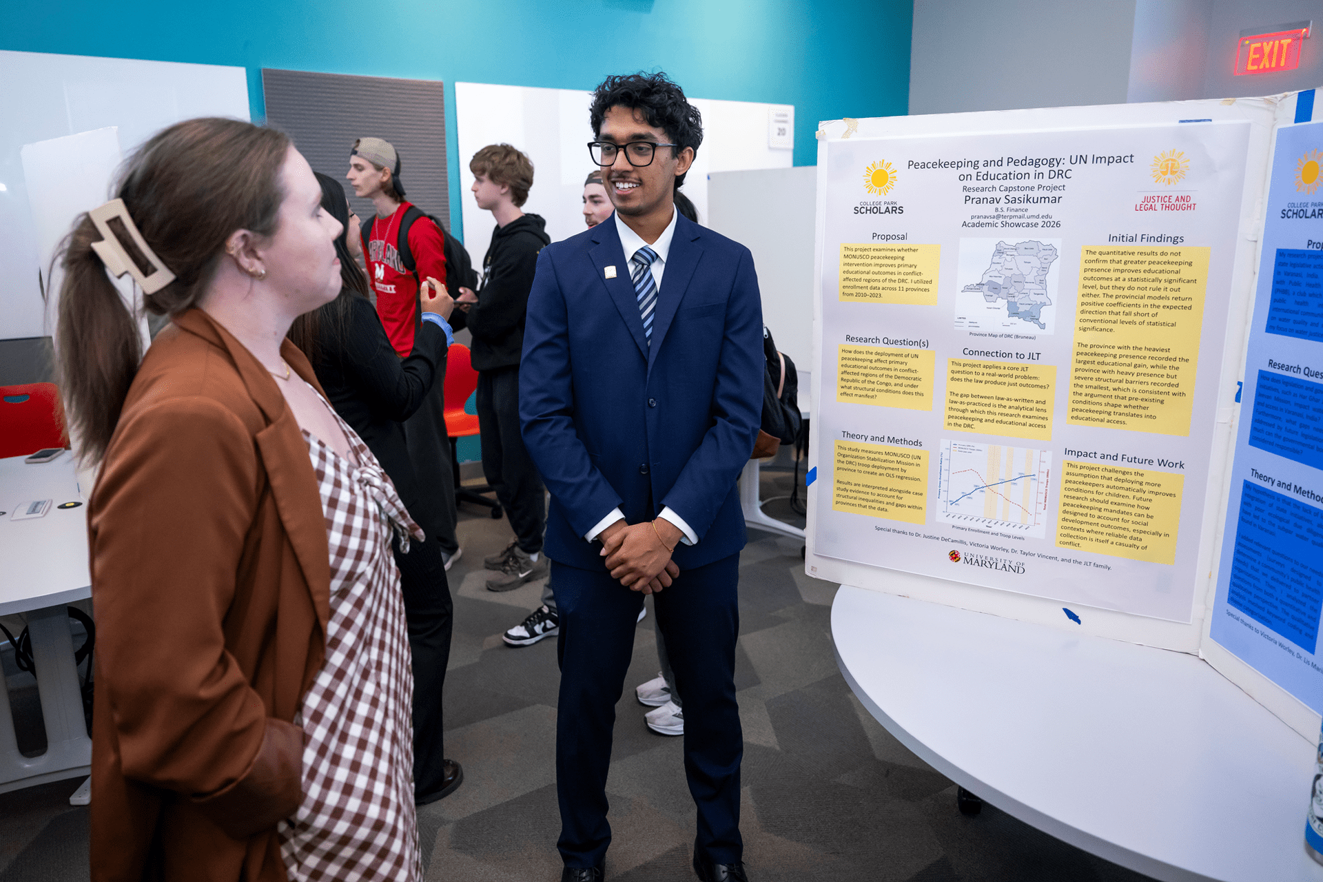 man in front of posterboard talking to woman