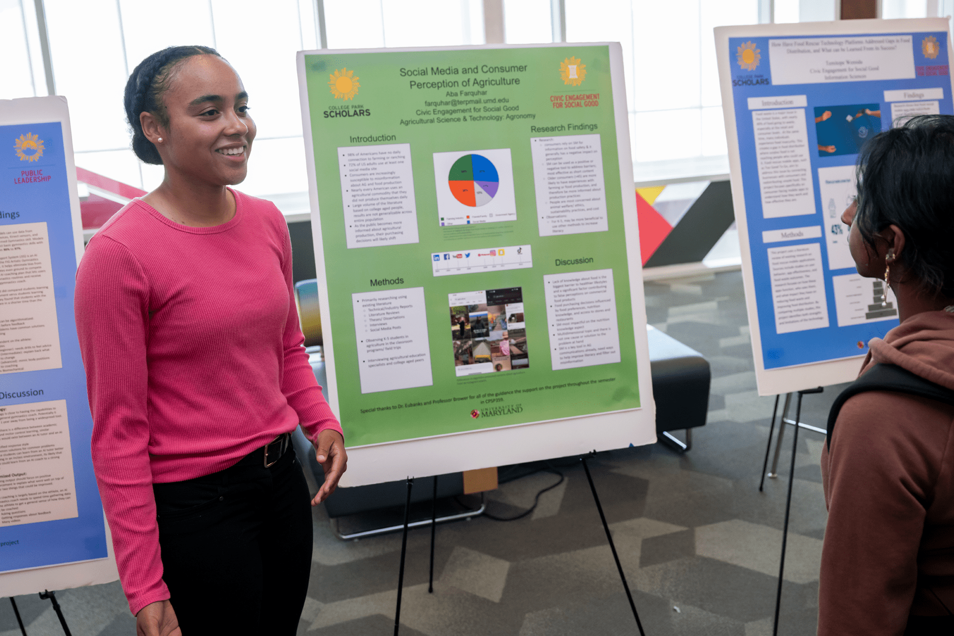 student smiling in front of poster with another student