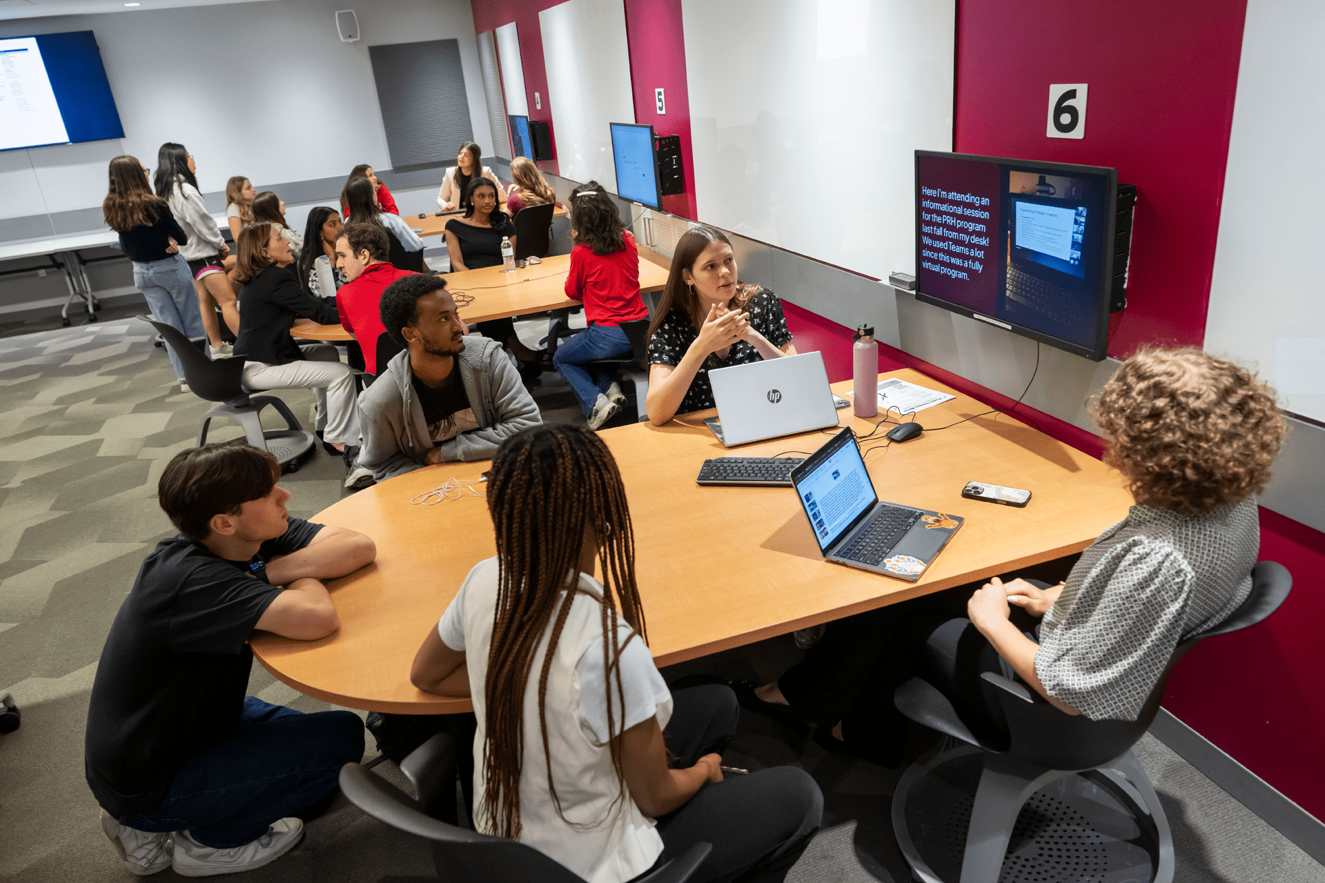 students sitting around a table looking at a screen on the wall