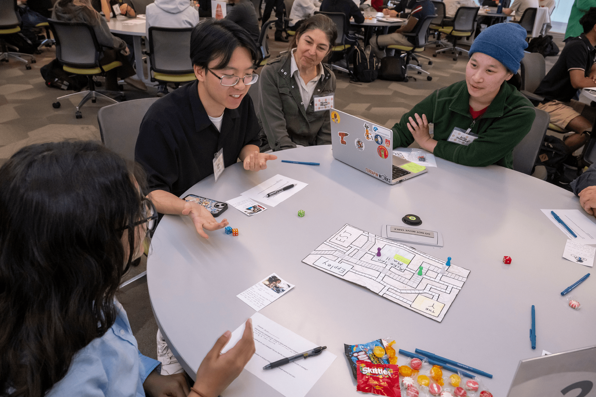 students sit around a table holding monopoly money