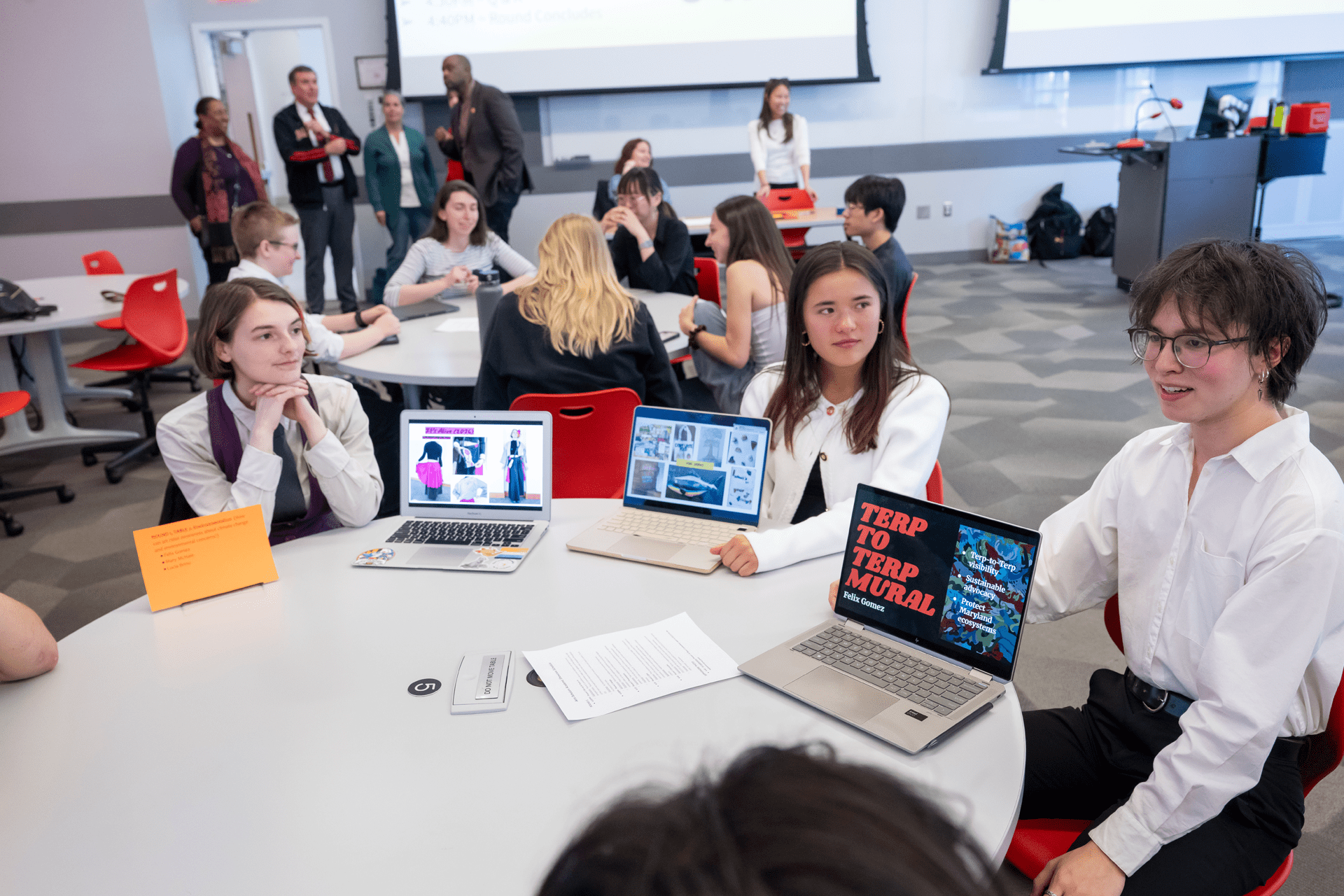 students sitting around a table with open laptops