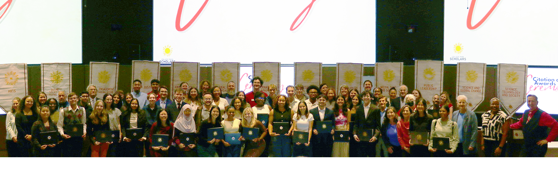 students smiling in front of Scholars program gonfalons